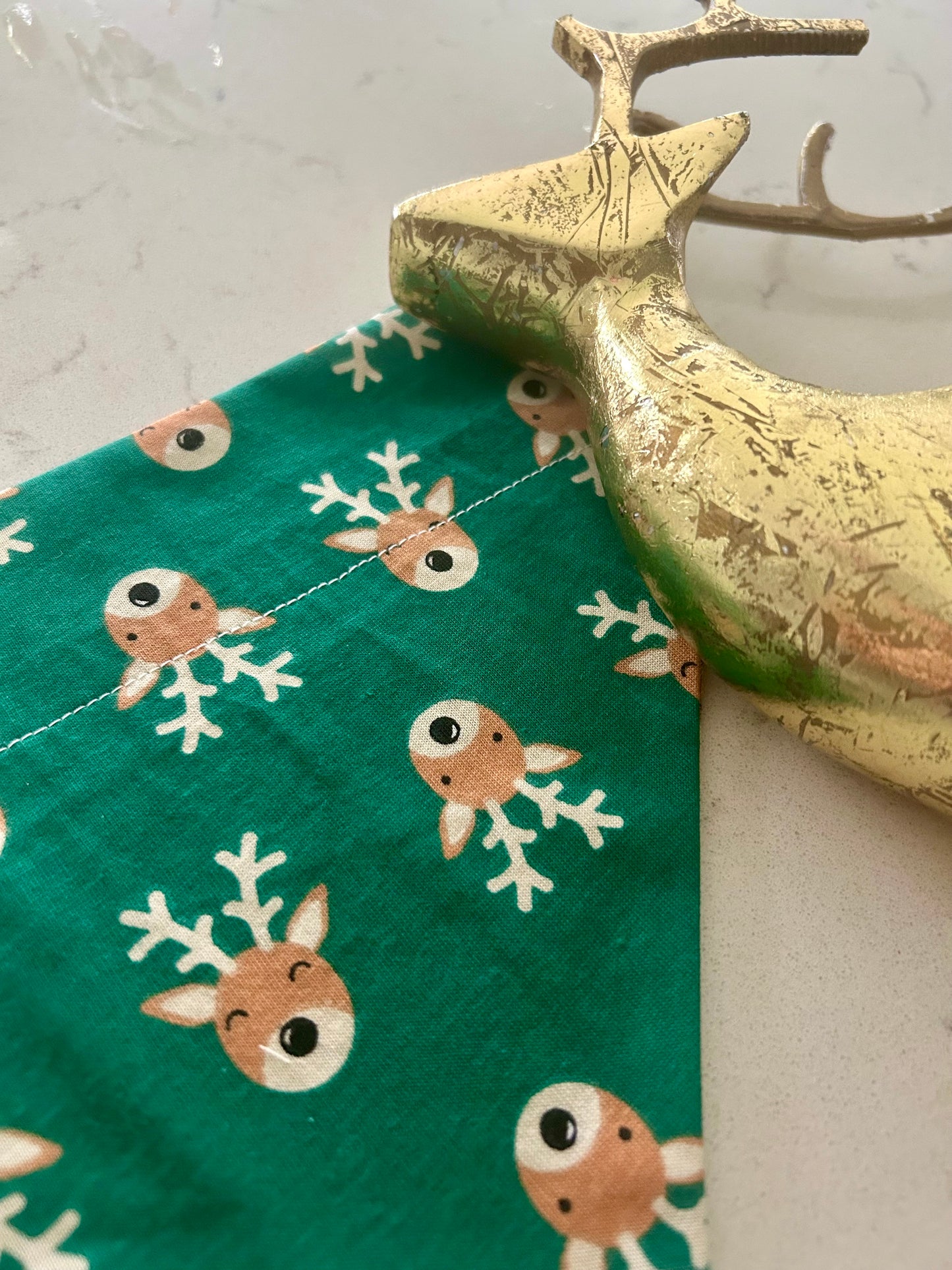 Green bandana with reindeer print, gold reindeer statue on white surface