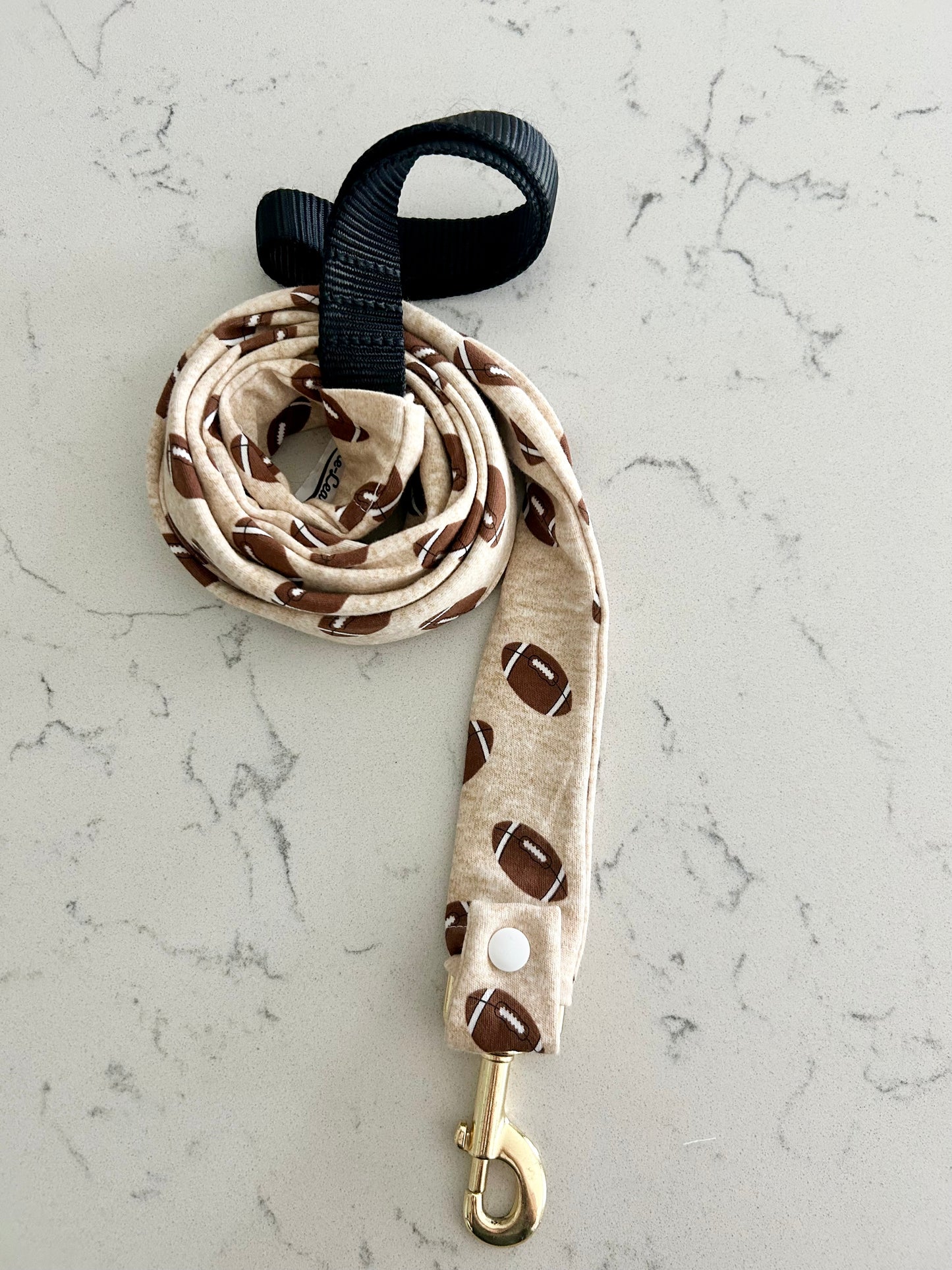 Dog leash with brown football pattern on a marble surface