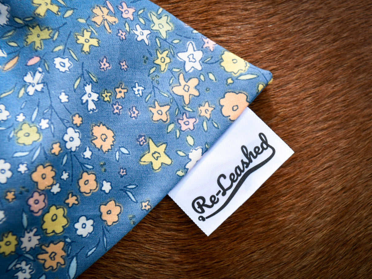 Close up blue floral bandana, releashed tag against brown dog fur